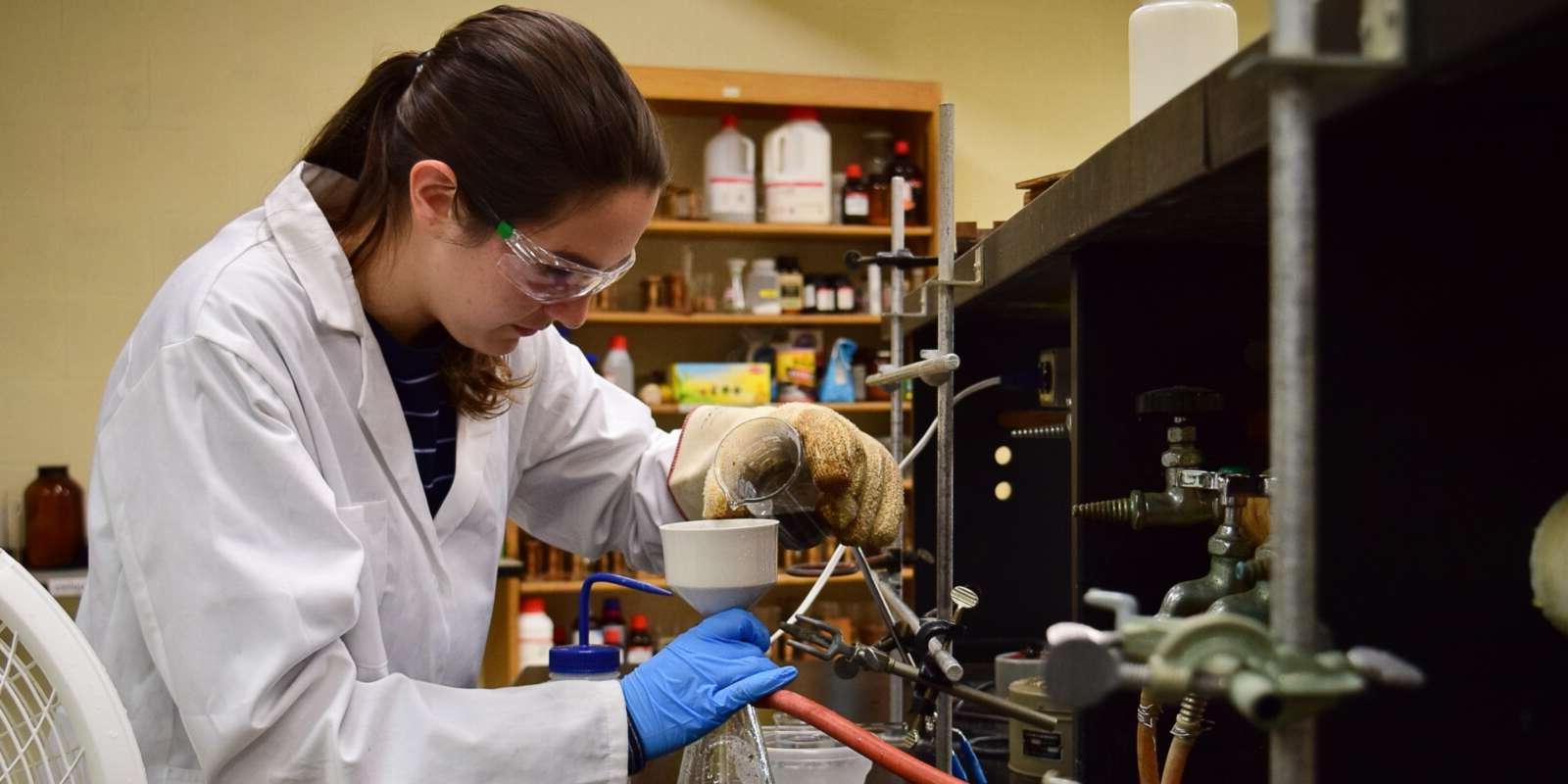 Student pouring solution from a beaker into a funnel